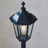 Endon Ashshaw bollard light in matt black die cast aluminium with a traditional lantern head, clear glass panels and a visible filament E27 bulb.