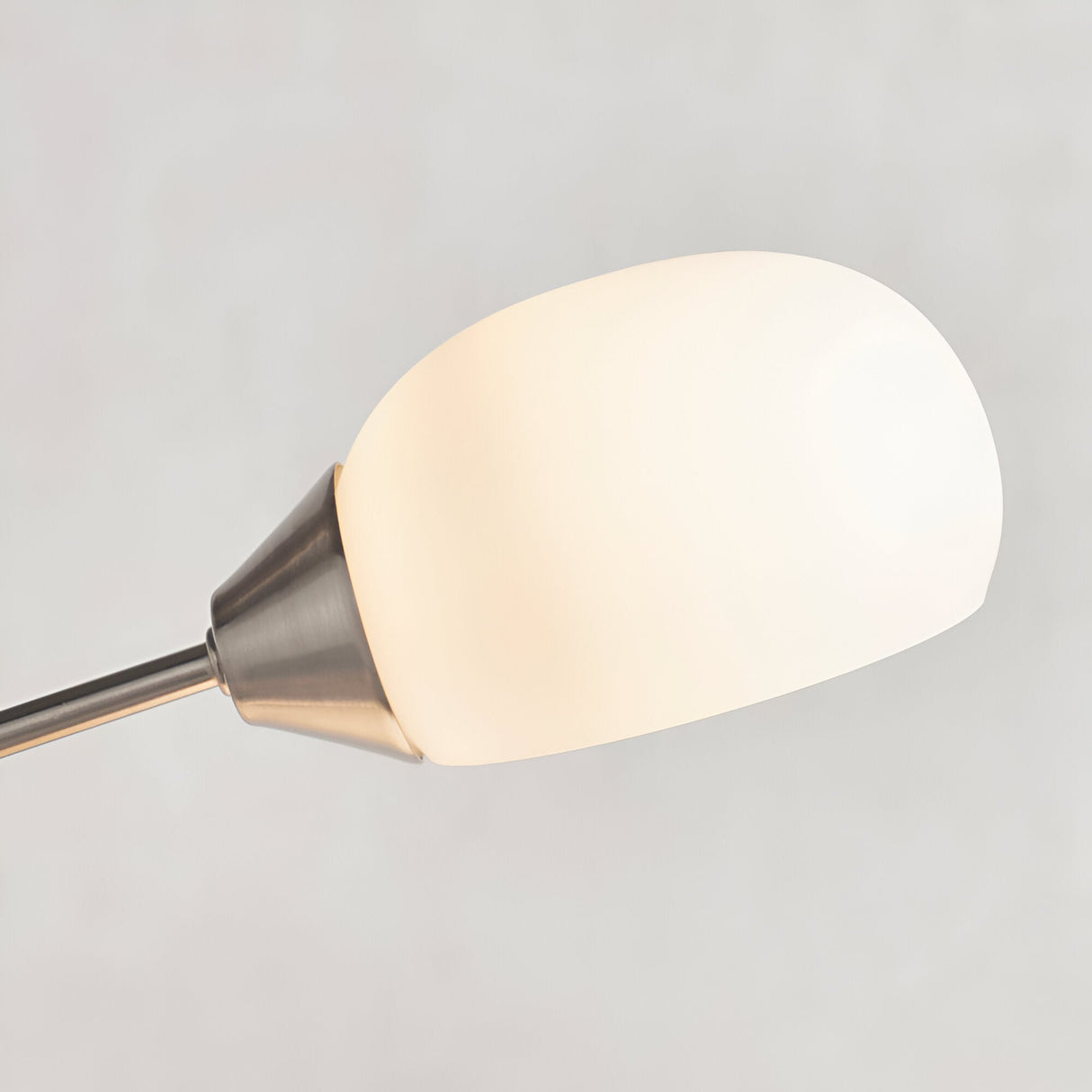 Close-up of the Endon Brockcombe floor lamp's white glass shade on a satin nickel arm, shown against a plain light grey background.