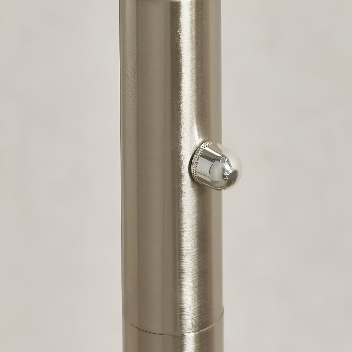 Close-up of the Endon Brockcombe floor lamp's satin nickel stem showing the central chrome rotary dimmer knob against a light background.
