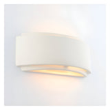 Endon Bramhurst wall light in un-glazed white ceramic, curved rectangular form casting a warm up-and-down glow against a plain white wall.