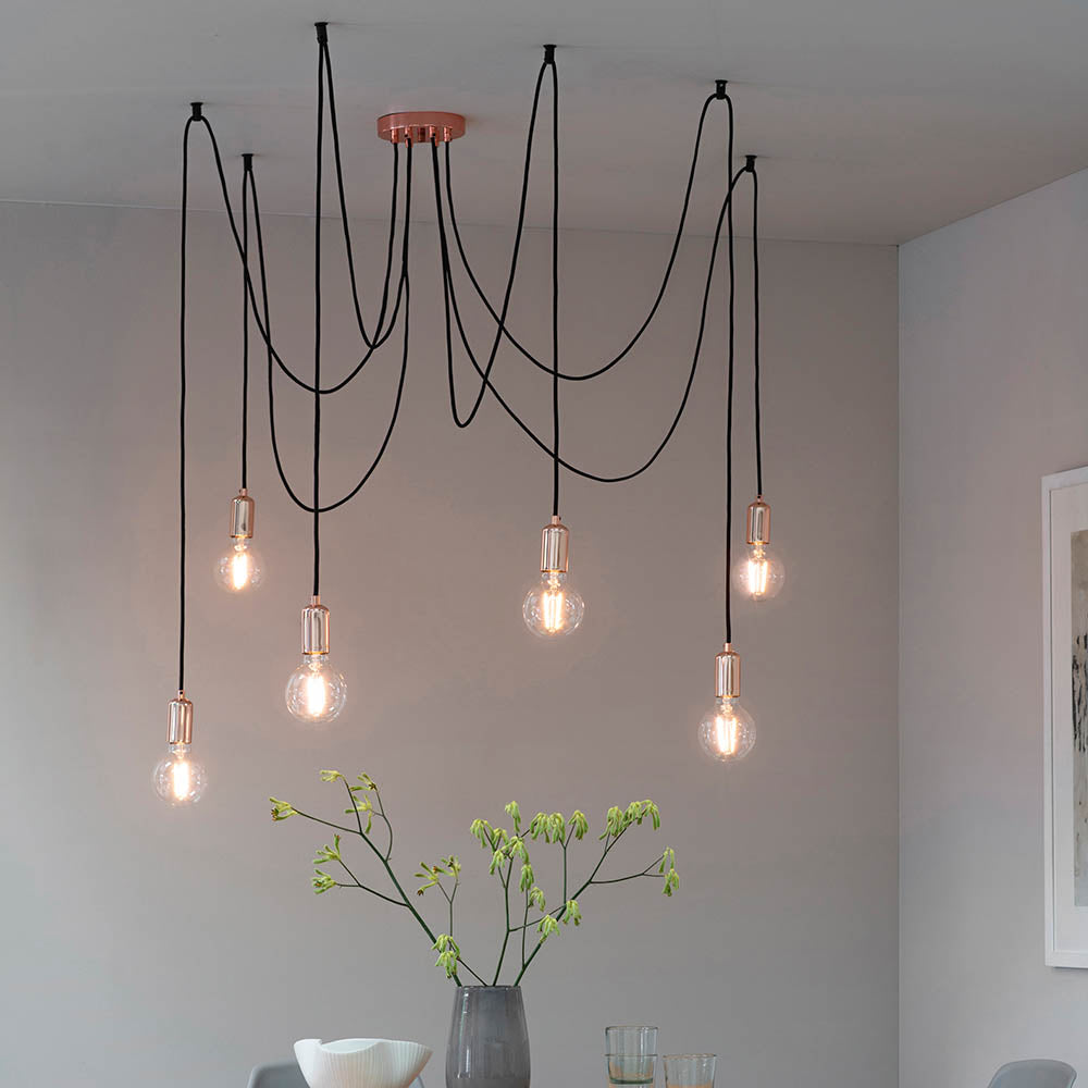 Endon Marlowe 6 Light Pendant in copper and black, with six E27 lamp holders on draped black fabric cables from a copper ceiling rose above a dining table.