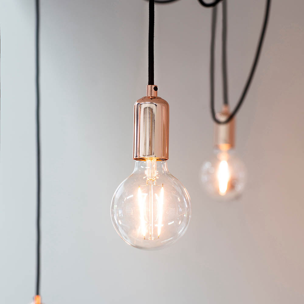 Endon Marlowe 6 Light Pendant in copper and black with exposed filament bulbs on black fabric cables against a pale grey wall.
