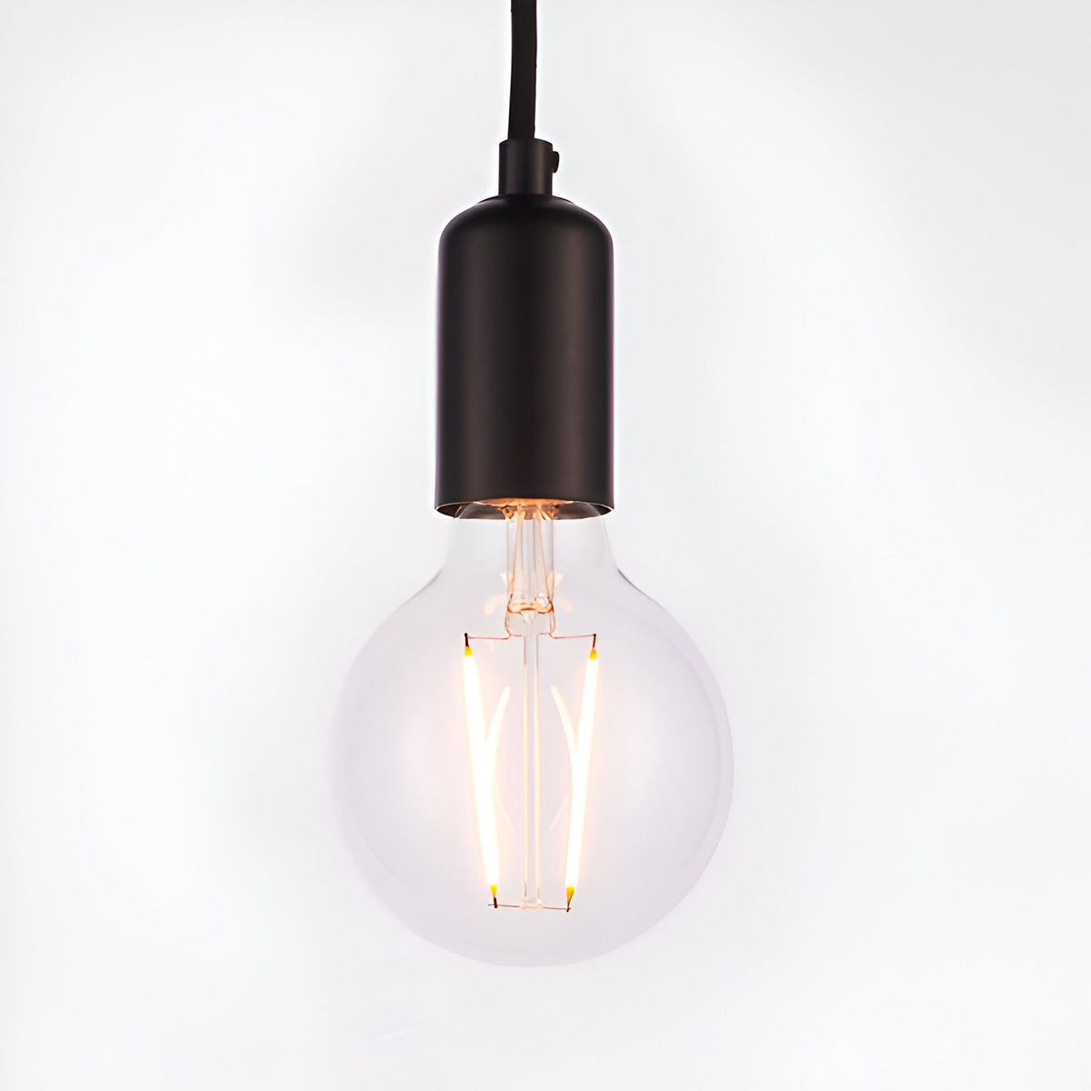 Endon Marlowe pendant light with a matt black E27 lamp holder on black fabric flex, fitted with a clear globe filament LED bulb, on white.