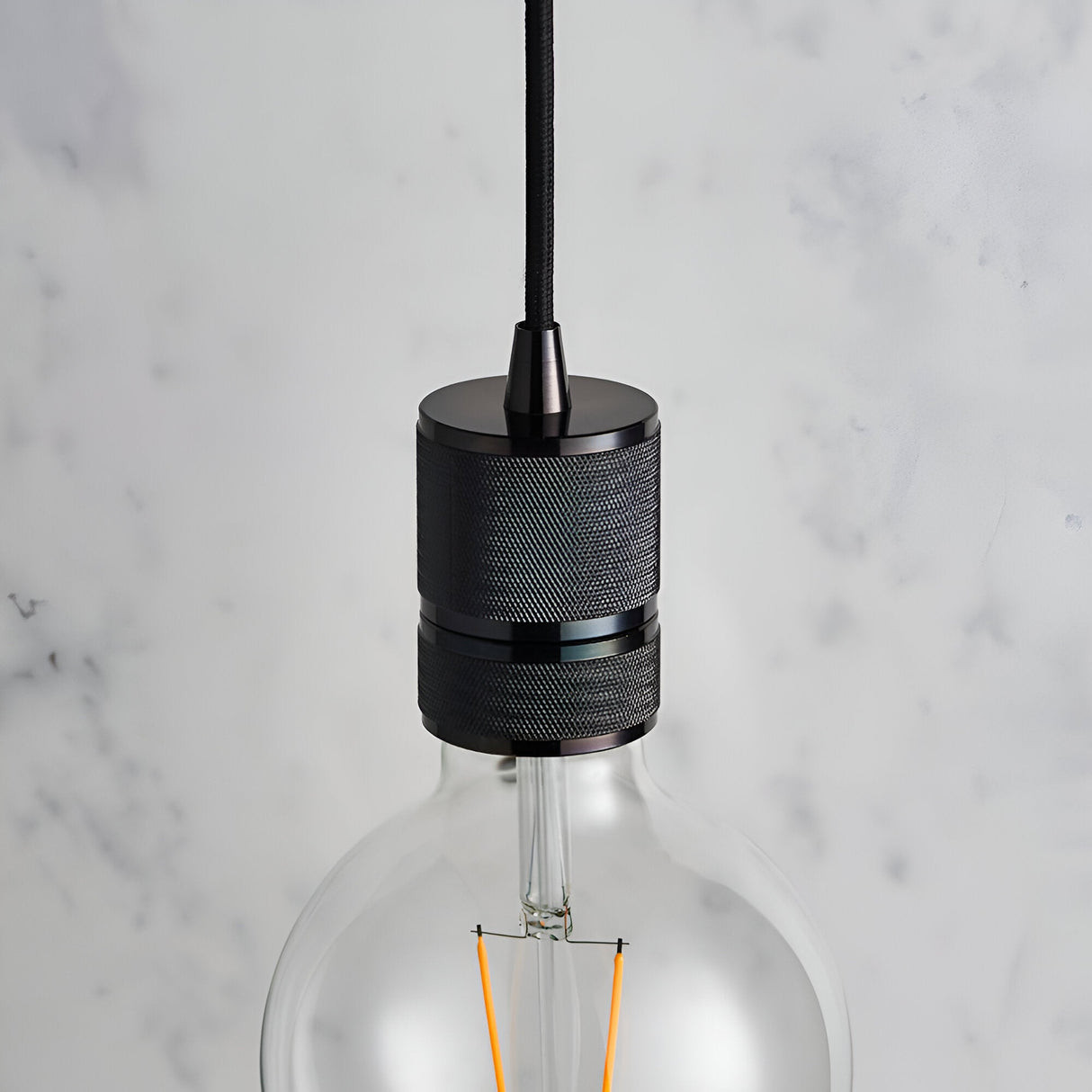 Endon Camden pendant light close-up showing black chrome knurled lamp holder on black fabric flex with an exposed E27 filament bulb against marble.