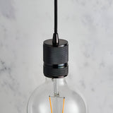 Endon Camden pendant light close-up showing black chrome knurled lamp holder on black fabric flex with an exposed E27 filament bulb against marble.