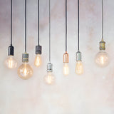 Endon Camden pendant lights in chrome, black, brass and copper finishes with exposed filament E27 bulbs on black flex cables against a light background.