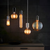 Endon Camden pendant lights in chrome and black clustered against a dark tiled wall, each holding an exposed filament E27 bulb in varied shapes.