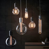 Endon Camden pendant lights in chrome and black clustered against a dark slate wall, each holding a decorative filament bulb on fabric flex.