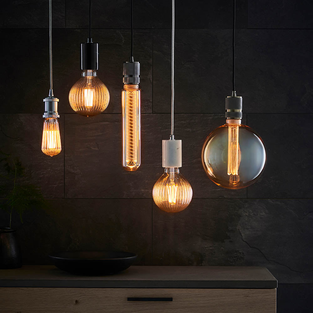 Endon Camden pendant lights grouped over a kitchen counter, showing brass and black cable fittings with exposed filament LED bulbs against dark slate tiling.