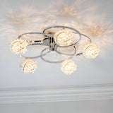 Endon Seraphine 5 light semi-flush ceiling light in polished chrome, illuminated crystal globe shades on circular arms casting patterns across the ceiling.
