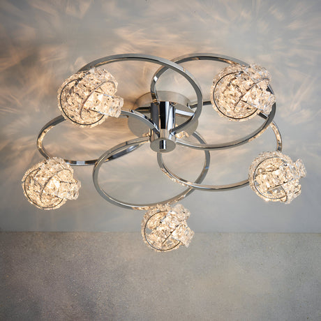 Endon Seraphine 5 light semi-flush ceiling light with polished chrome rings and crystal globe shades, shown lit against a pale wall.