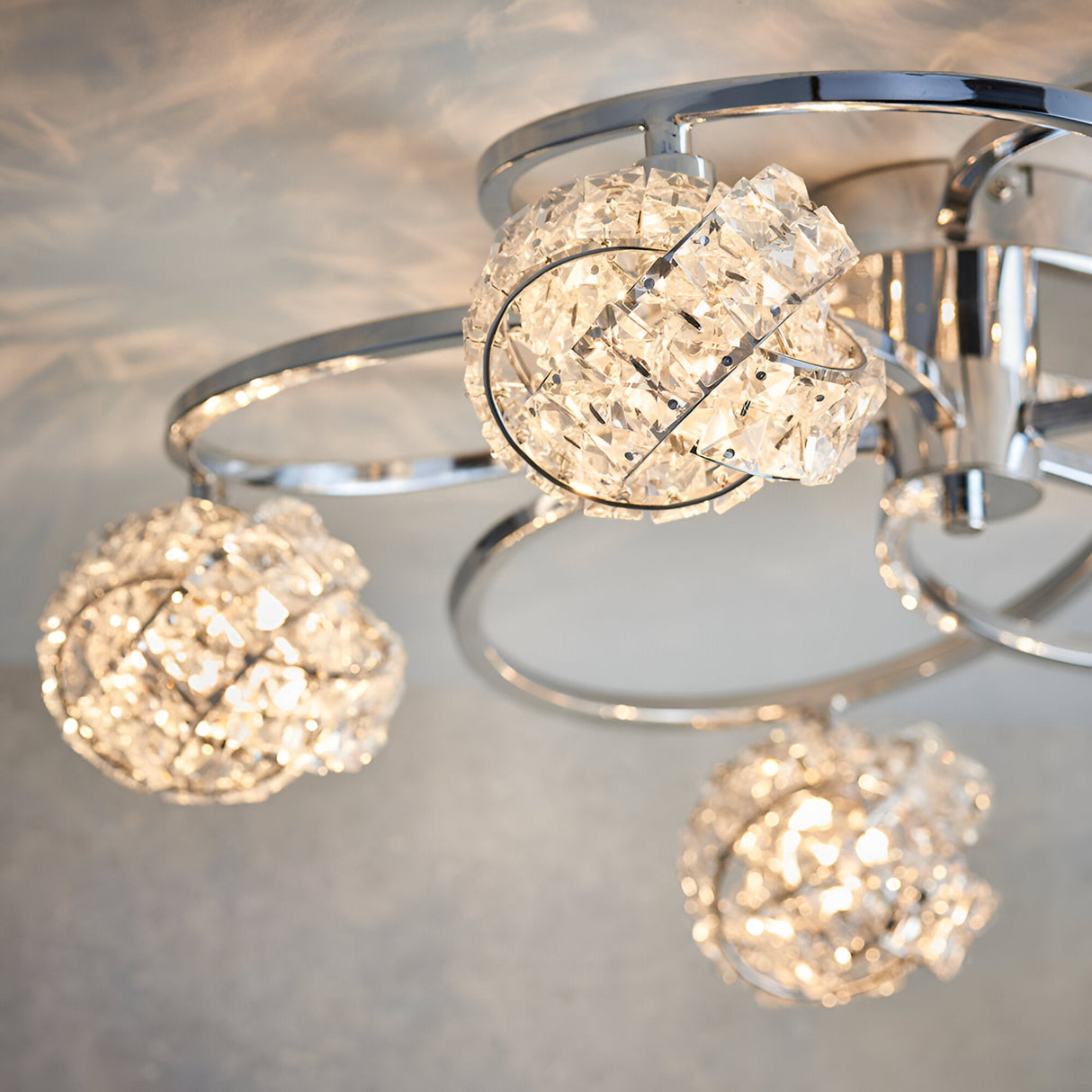 Close-up of the Endon Seraphine 5 light semi-flush ceiling light with polished chrome arms and crystal globe shades casting sparkle across the ceiling.