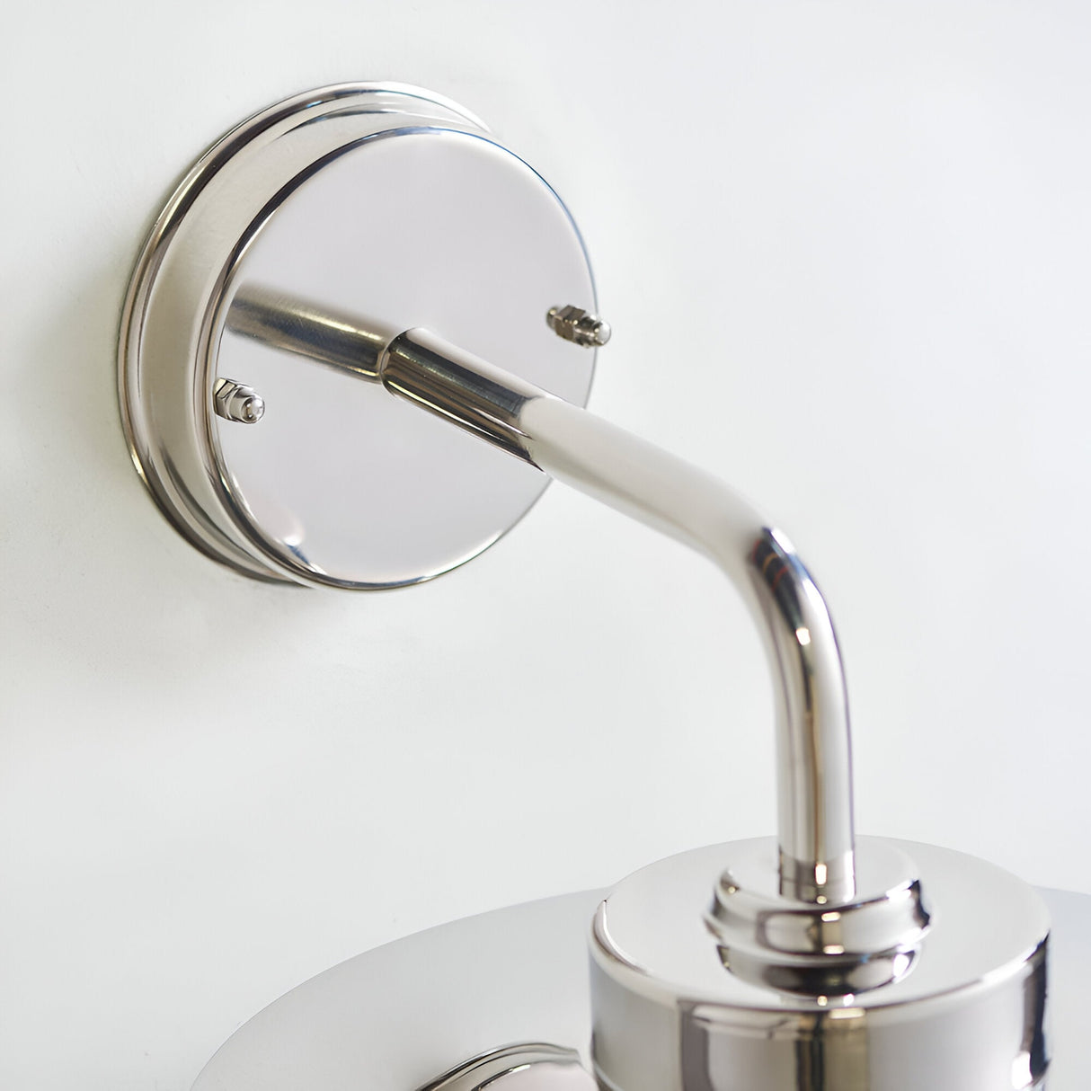 Close-up of the Endon Aldbury outdoor wall light showing its polished stainless steel wall plate, curved arm and fitting against a plain white wall.