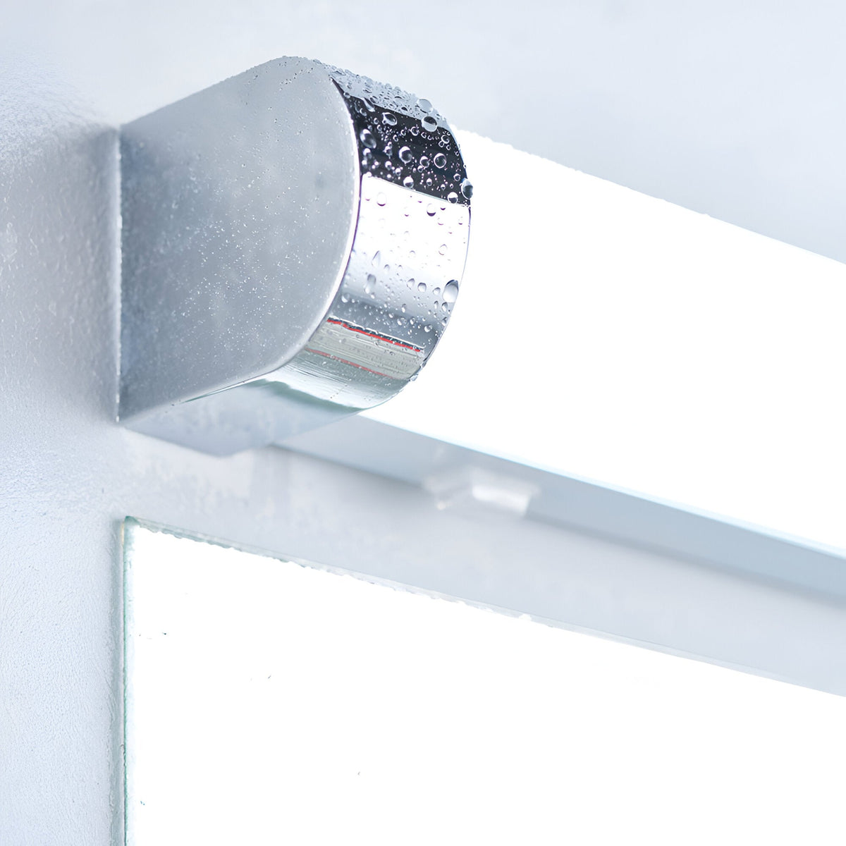 Close-up of the Endon Carlshaw LED bathroom wall light, showing the chrome cylindrical end cap and white ribbed diffuser mounted above a mirror.