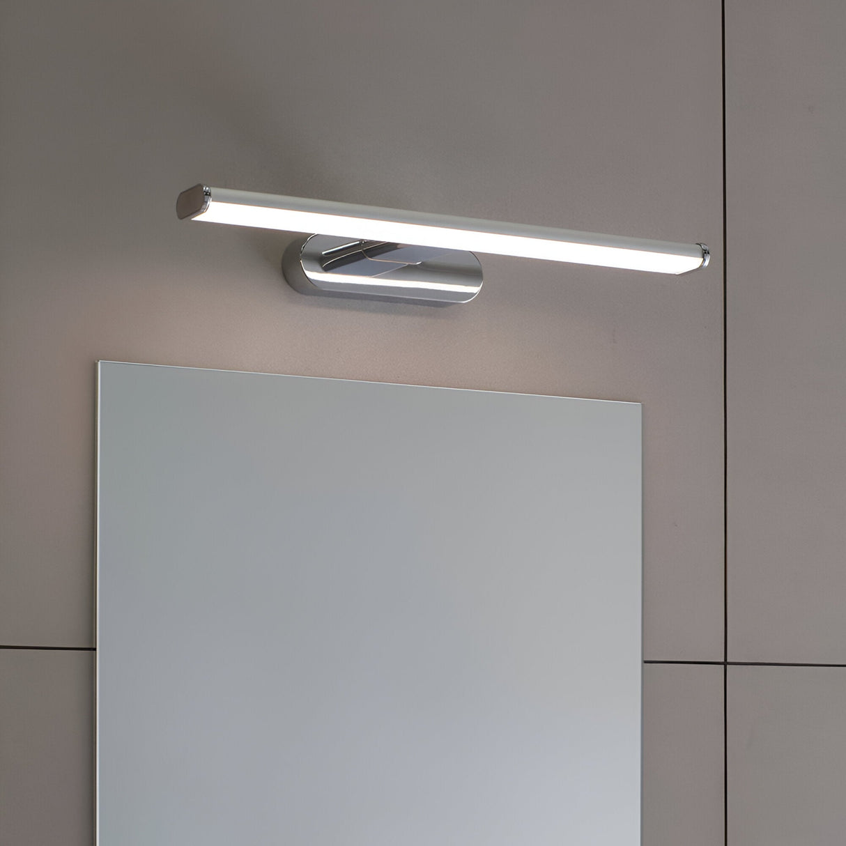 Carlshaw LED bathroom wall light in chrome with a frosted opal diffuser, mounted above a mirror on a light grey wall, illuminated.