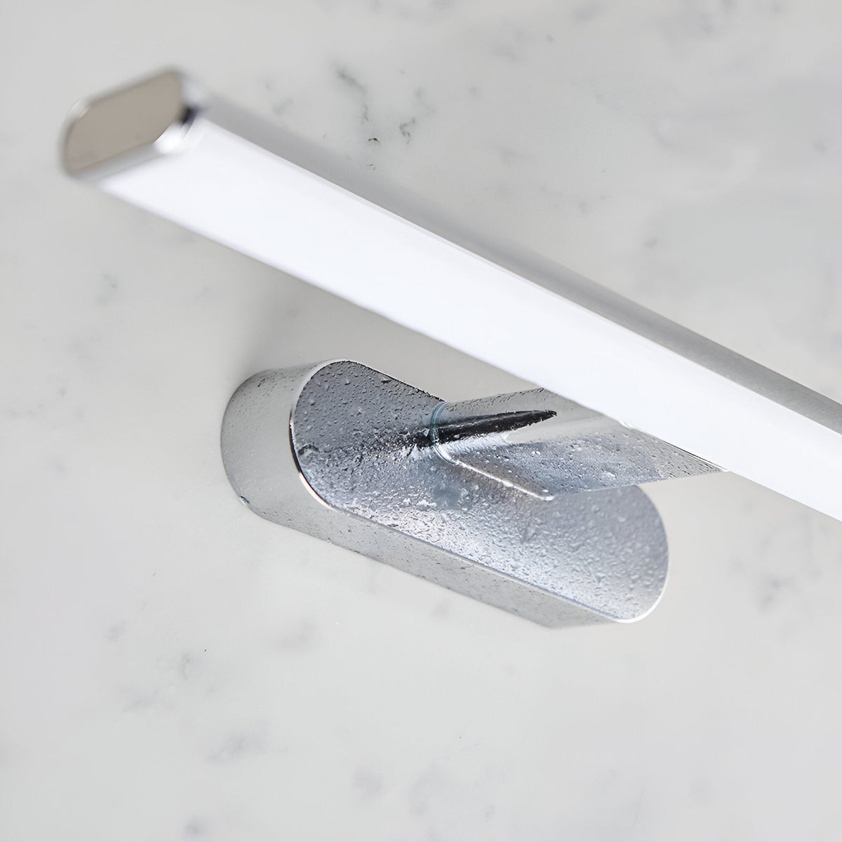 Carlshaw LED bathroom wall light with chrome mounting bracket and elongated frosted opal diffuser, shown on a marble surface.