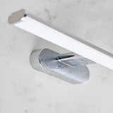 Carlshaw LED bathroom wall light with chrome mounting bracket and elongated frosted opal diffuser, shown on a marble surface.