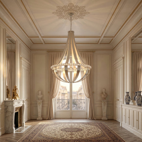 Elegant, sunlit room with ornate molding, marble fireplace, antique busts and vases. A Tessaro LED K9 Crystal & Leather Small Chandelier in grey hangs overhead. Tall windows with sheer curtains open to a balcony and classic architecture outside.