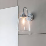 Endon Aldhurst chrome bathroom wall light with clear glass bell shade, E14 filament bulb and pull cord switch, mounted beside a mirror.