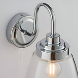 Endon Aldhurst bathroom wall light close-up showing polished chrome backplate, curved arm, and clear glass shade with an E14 filament bulb.
