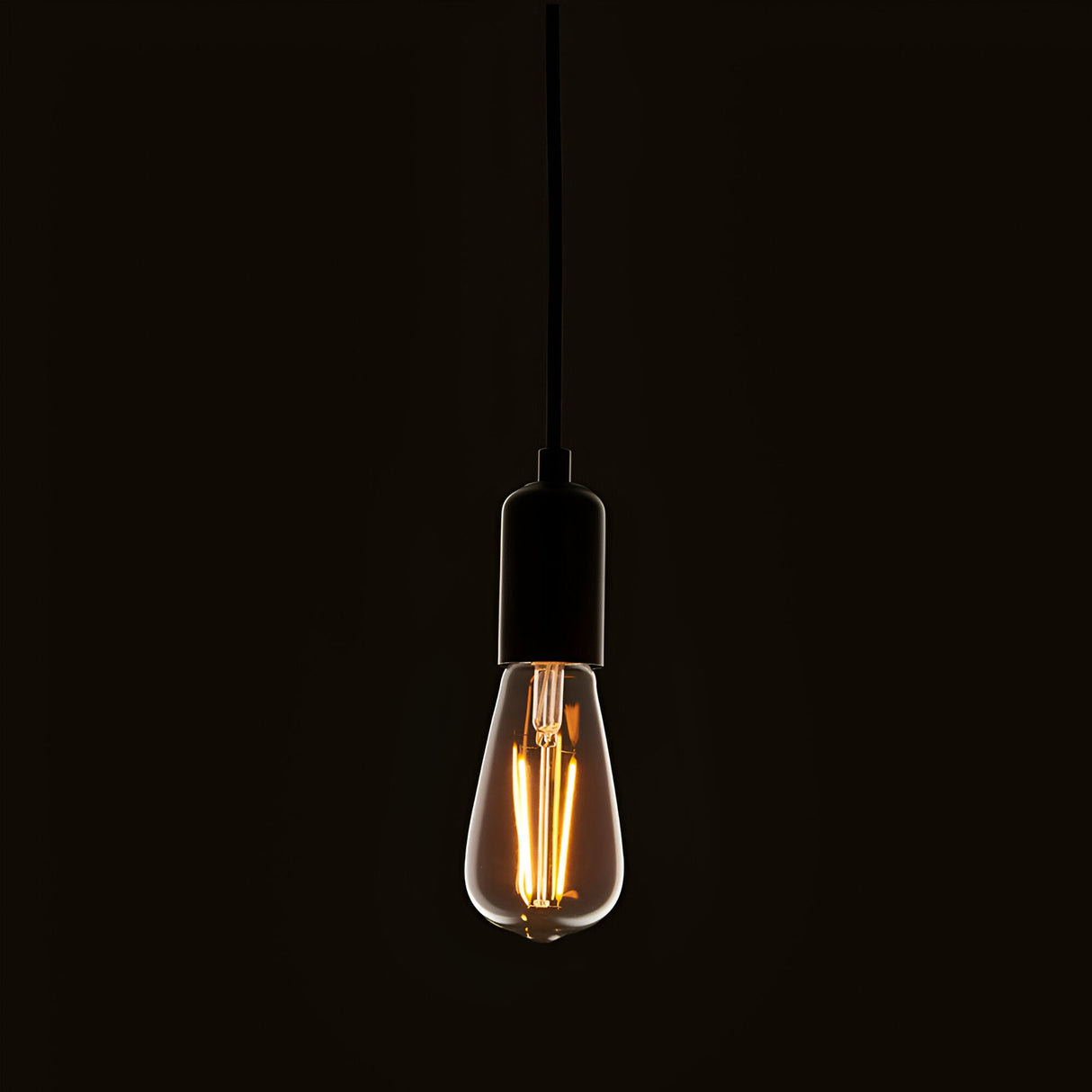 Endon 2W E27 LED filament pear bulb with clear glass and warm white glow, suspended from a black pendant cord holder against a dark background.