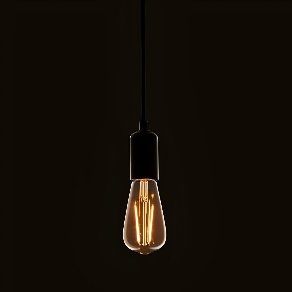 Endon 2W E27 LED filament pear bulb with amber tinted glass, suspended from a black pendant cord and matte black lampholder against a dark background.