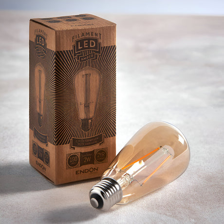 Endon 2W E27 LED amber filament pear bulb resting beside its printed kraft cardboard box on a light neutral surface.