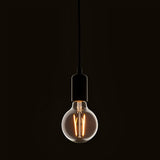 Pendant light fitted with a clear E27 LED filament globe bulb, glowing warm white against a dark background.