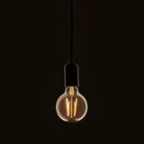 Pendant light fitted with a 2W E27 LED filament globe bulb in amber tinted glass, glowing warm white against a dark background.
