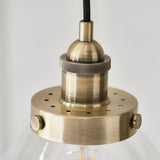 Close-up of Endon Wentworth Pendant Light in brass, showing the knurled E27 lamp holder, perforated disc and black fabric flex above a clear glass shade.