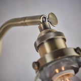 Close-up of the brass Wentworth Wall Light showing the adjustable knuckle joint, knurled lamp holder, and clear glass shade.