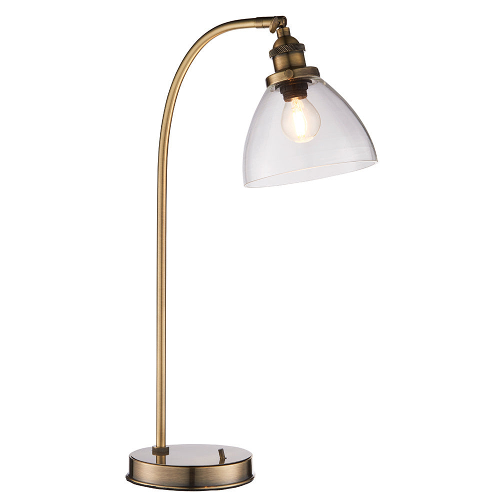 Wentworth Table Lamp in brass with a curved metal base, adjustable knuckle joint, and clear glass shade over an exposed bulb, shown on a white background.