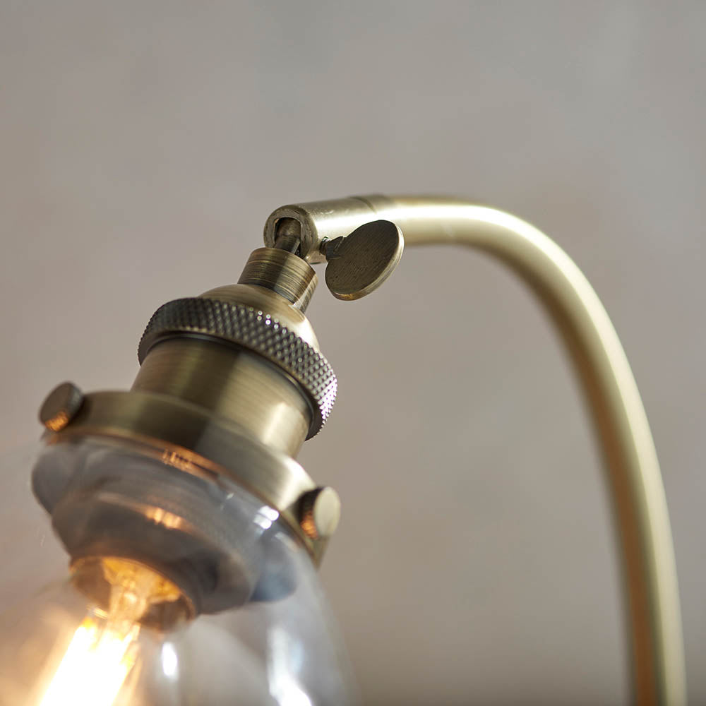 Close-up of the Wentworth Table Lamp in brass, showing the knurled lamp holder, adjustable knuckle joint, and clear glass shade with visible bulb.