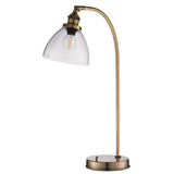 Wentworth Table Lamp in brass with an adjustable curved arm, clear glass dome shade and exposed bulb, on a round base against a white background.