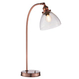 Endon Wentworth table lamp in copper with a curved arm, clear glass dome shade, knurled lamp holder and round base, shown on a white background.