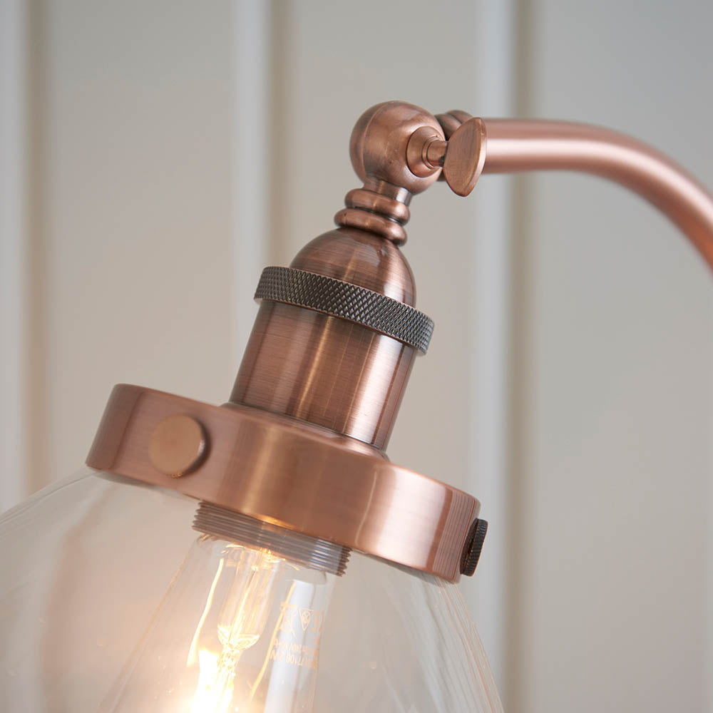 Close-up of Endon Wentworth floor lamp in copper, showing knurled E27 lamp holder, adjustable knuckle, clear glass shade and visible filament bulb.