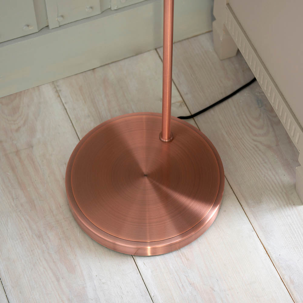Endon Wentworth floor lamp base in copper finish, showing the circular weighted base and stem on light wood plank flooring beside skirting.