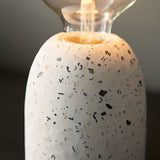 Close-up of the Endon Crangrove table lamp's white terrazzo base with black and grey speckled flecks, topped by an exposed filament globe bulb.