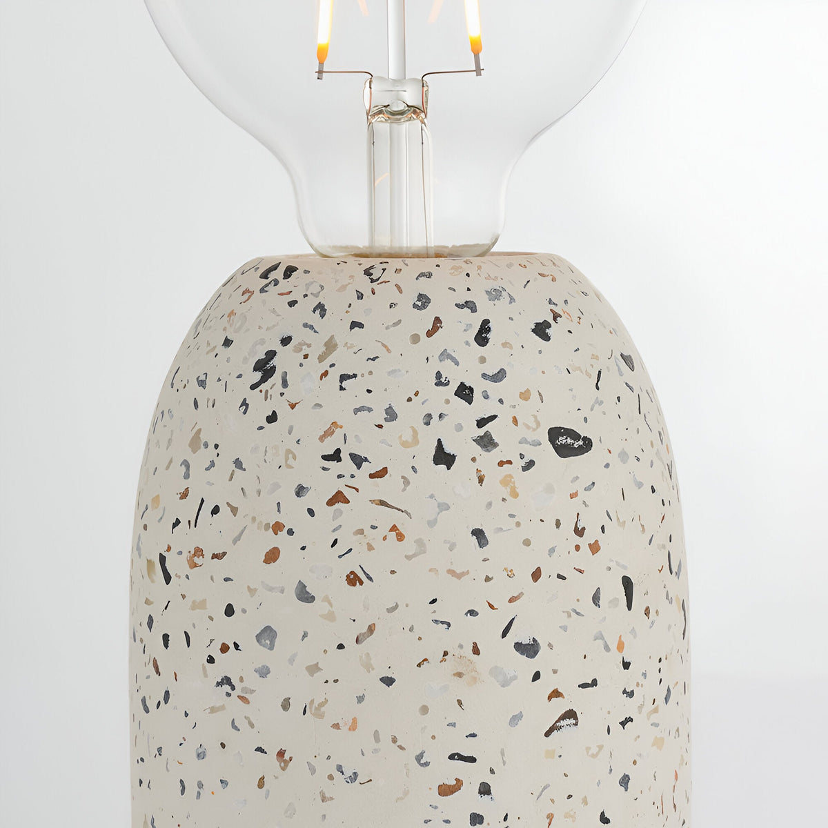 Endon Crangrove table lamp close-up showing the white terrazzo base with multicoloured aggregate flecks and exposed E27 filament globe bulb.