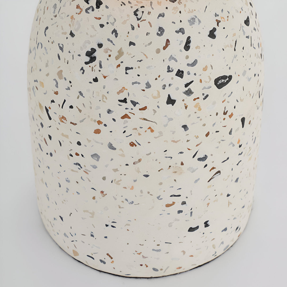Close-up of the Endon Crangrove table lamp's white terrazzo base, showing matt speckled composite with black, grey and warm brown aggregate flecks.
