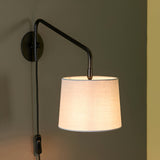 Endon Bevbourne plug-in wall light with matt black swing arm, in-line switch on black fabric flex, and light grey cotton-mix drum shade.