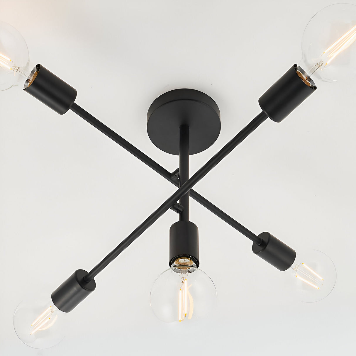 Endon Marlowe 5 light semi-flush ceiling light in black, with crossed metal arms and exposed E27 globe bulbs, viewed from below against a white ceiling.