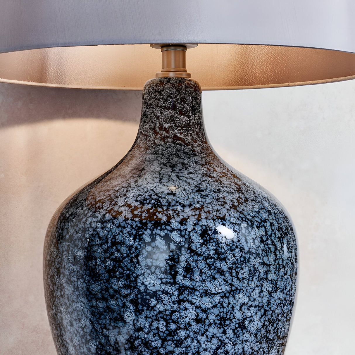 Close-up of Endon Brenwick table lamp showing black speckled glass body with blue-grey detailing, matt nickel collar and mink faux silk tapered shade.
