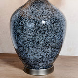 Close-up of the Endon Brenwick table lamp base showing black speckled glass with grey mottling on a brushed nickel foot, set on a wooden surface.