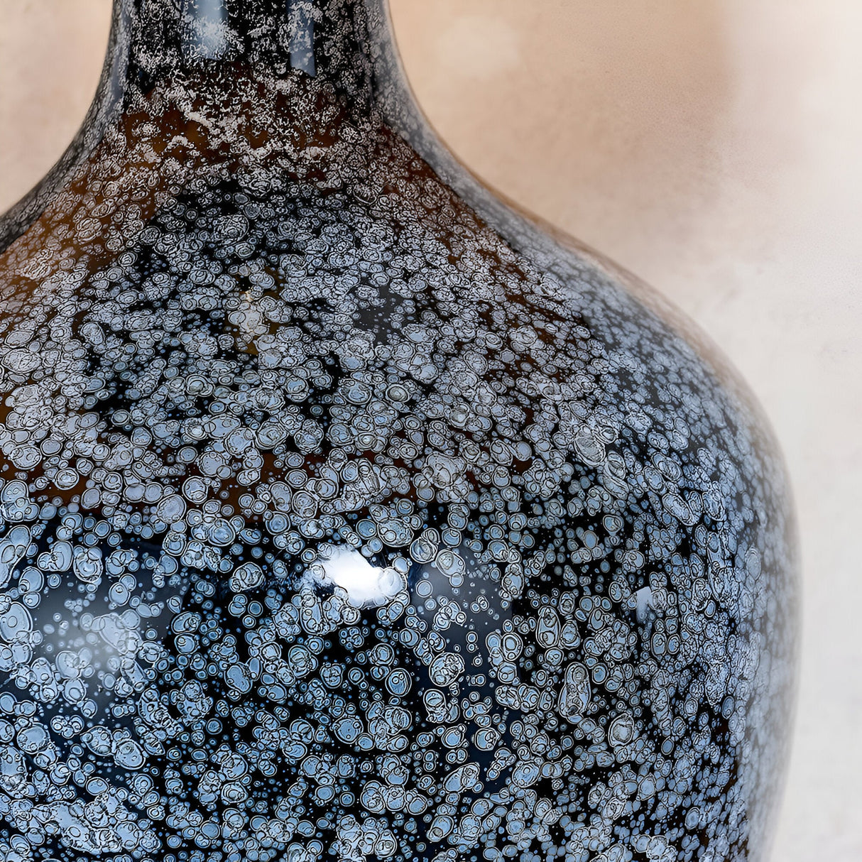 Close-up of the Endon Brenwick table lamp showing its black glass body with grey speckled detailing and matt nickel neck fitting.