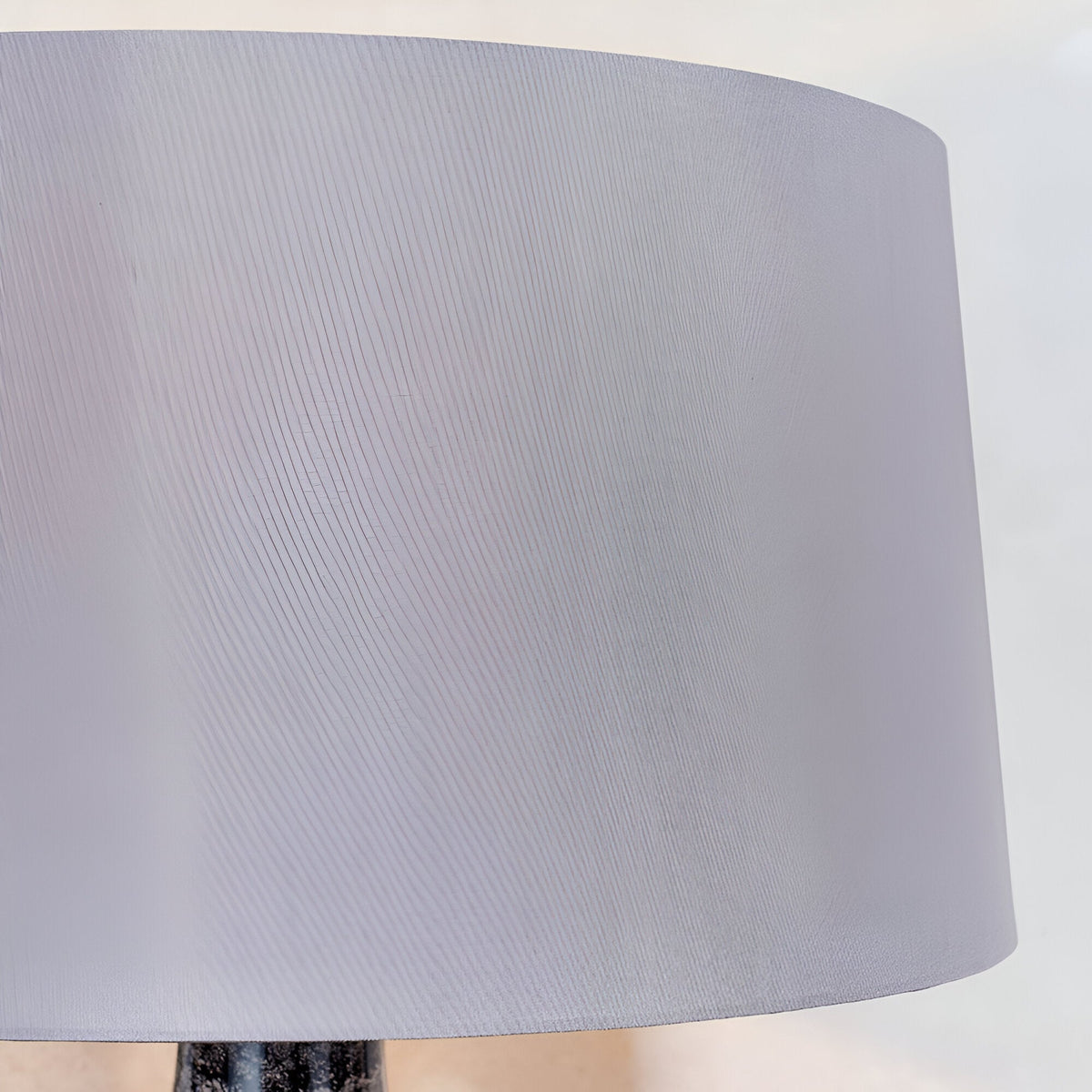 Close-up of the Endon Brenwick table lamp's mink faux silk tapered drum shade above the black speckled glass base.