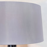 Close-up of the Endon Brenwick table lamp's mink faux silk tapered drum shade above the black speckled glass base.