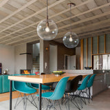 Global Globe Pendant Light - 60cm clear acrylic sphere shade with bronze metal suspension, shown above a wooden dining table in a modern kitchen setting.