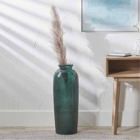 Sea Green Recycled Glass Ribbed Vase, tall ribbed floor vase in green glass with pampas grass, shown beside a wooden side table in a living room setting.