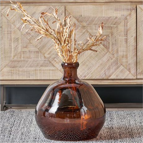 Pecan Brown Organic Shaped Recycled Glass Vase, 50cm, bulbous glass form with narrow neck, holding dried foliage stems, set on a rug against a wood-panelled sideboard.